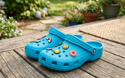 Turquoise garden clogs with colorful charms on a wooden deck